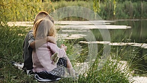 A little boy hugs his little sister while sitting on the shore