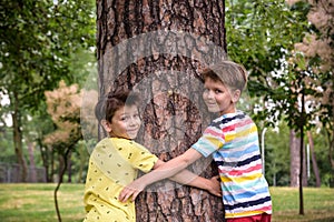 Little boy hugs a tree trunk - children love the nature, sustainability concept. Save the nature