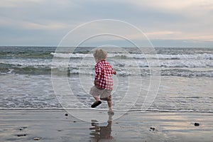 A little boy is jumping and dancing by the ocean