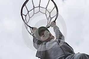 A little boy jumping and making goal playing streetball, basketball. Throws a basketball ball in the ring. The concept of sport