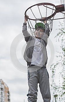 A little boy jumping and making goal playing streetball, basketball. Throws a basketball ball in the ring. The concept of sport