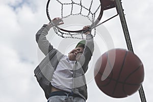 A little boy jumping and making goal playing streetball, basketball. Throws a basketball ball in the ring. The concept of sport