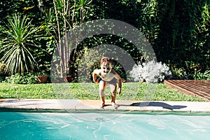Little boy jumping in a pool. Child get fun in the swimming pool of his home. Outdoors activities in quarantine photo