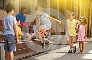 Little boy jumping on rubber band with friends in historical center