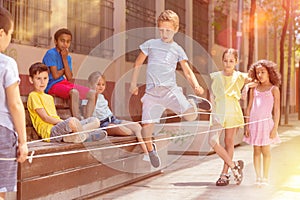 Little boy jumping on rubber band with friends in historical center