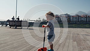 Little boy on kick scooter in park. Preschool kid learn to skate roller board. Smiling child skating on sunny summer day