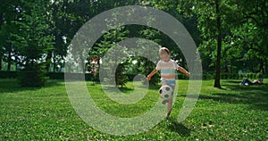 Little boy kicking soccer ball. Focused child practicing in summer park alone.