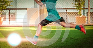 Little boy kicking a soccer ball in sport training session with motion blur and light effect