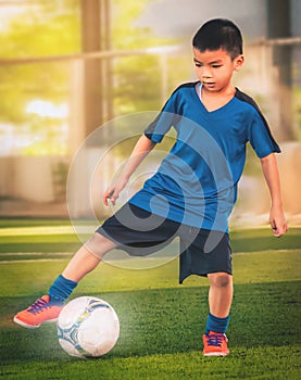 Little boy kicking a soccer ball in sport training session with motion blur and light effect