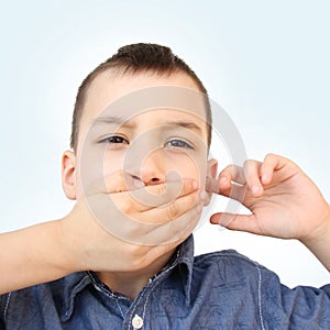 Little boy, kid covered his mouth with his palm, bit his tongue, stomatitis, clings to his ear, close-up, medical concept, autism