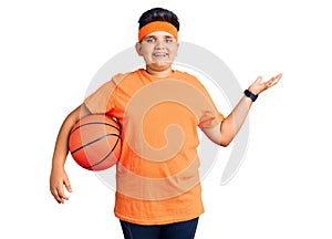 Little boy kid holding basketball ball celebrating victory with happy smile and winner expression with raised hands