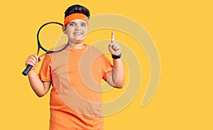 Little boy kid playing tennis holding racket surprised with an idea or question pointing finger with happy face, number one