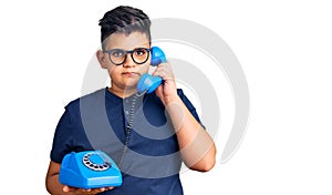 Little boy kid using vintage telephone thinking attitude and sober expression looking self confident