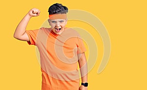 Little boy kid wearing sportswear angry and mad raising fist frustrated and furious while shouting with anger
