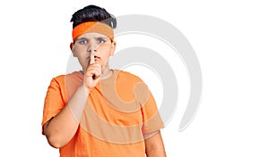 Little boy kid wearing sportswear asking to be quiet with finger on lips