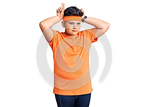 Little boy kid wearing sportswear doing bunny ears gesture with hands palms looking cynical and skeptical