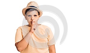 Little boy kid wearing summer hat and hawaiian swimsuit asking to be quiet with finger on lips