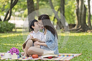 Little boy kiss her mom. Happy asian family having fun outside and sitting picnic in the park