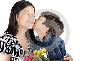 Little boy kissing his mother with flower