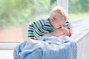 Little boy kissing newborn baby brother