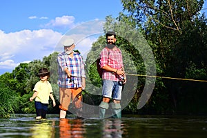 Little boy on a lake with his father and grandfather. Happy fisherman with fishing rod. 3 men fishing on river in summer