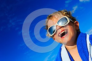 Little boy laugh wrapped in beach towel on sky
