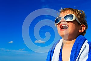 Little boy laugh wrapped in beach towel on sky