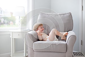 Little boy laughing in chair wearing diaper