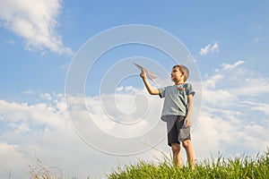 Little boy launches a paper plane into the air. Child launches a paper plane. Happy kid playing with paper airplane