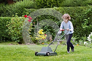 Little boy with a lawn mower in the garden