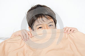 Little boy lay on bed with blanket cover half face
