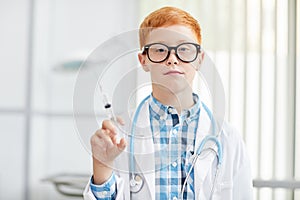 Little Boy laying Doctor and Holding Syringe