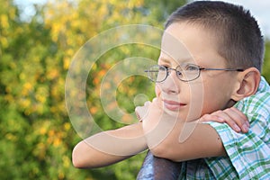 Little boy is lean elbow on bridge fence