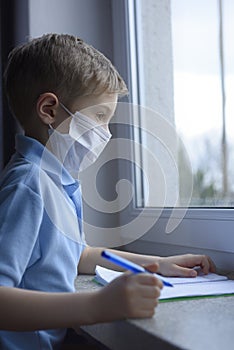 Little boy is  learning in a medical mask.