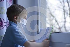 Little boy is  learning in a medical mask.