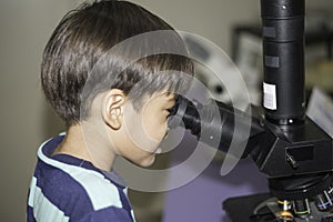 Little boy learning science class with microscope in the class