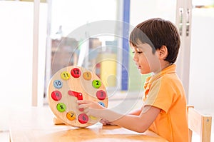Little boy learning time with clock toy of montessori educational materials