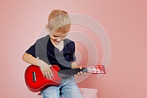 Little boy is learning to play on a small guitar. Study music. Ukulele