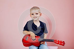 Little boy is learning to play on a small guitar. Study music. Ukulele