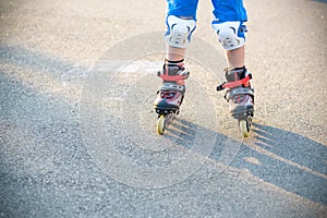 Little boy learning to roller skate in summer park. Children wearing protection pads for safe roller skating ride. Active outdoor