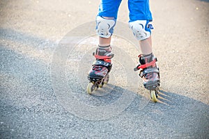 Little boy learning to roller skate in summer park. Children wearing protection pads for safe roller skating ride. Active outdoor