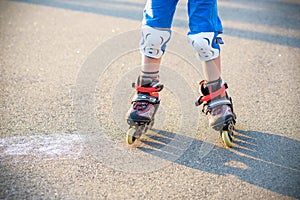 Little boy learning to roller skate in summer park. Children wearing protection pads for safe roller skating ride. Active outdoor