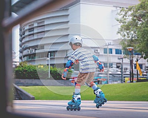 Little Boy is learning to Skate on an Rollerblade in park with full protection gear and helmet