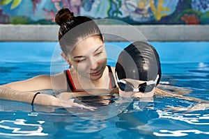 Little boy learning to swim in pool with teacher