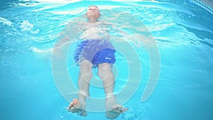 little boy learning to swim in the swimming pool