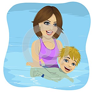 Little boy learning to swim in a swimming pool, mother holding child