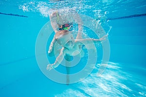 Little boy learning to swim underwater in pool