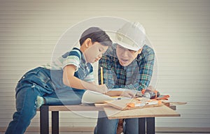 Little Boy learning to work on wood and be a builder from his craftman father in vintage tone for Family bonding and