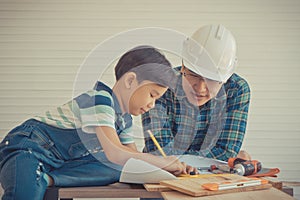 Little Boy learning to work on wood and be a builder from his craftman father in vintage tone, Family working together on house