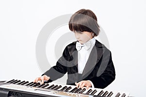 The little boy learns the game on the synthesizer. The dark-haired boy in the suit plays keyboards.